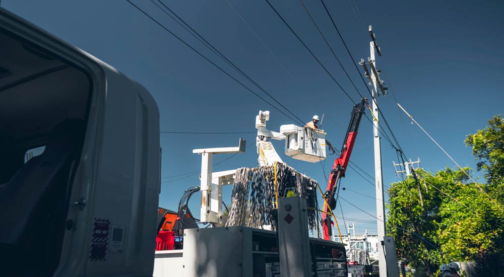 Crews up in a bucket truck working next to power pole