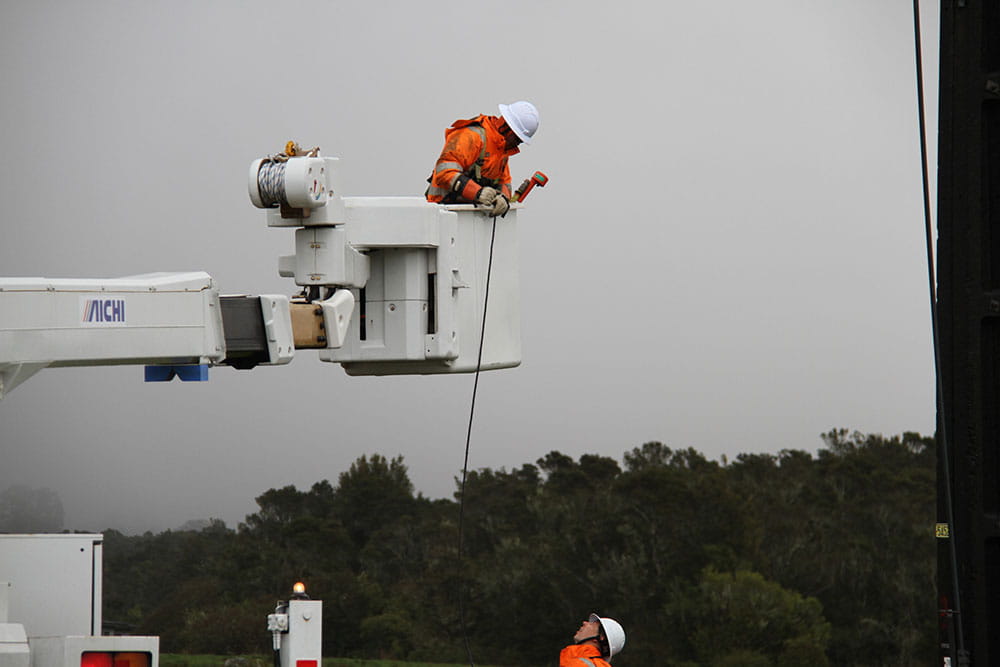 Crew member in a cherry picker talking to crew on the ground.