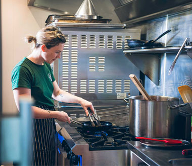 women cooking on gas stove in restaurant kitchen