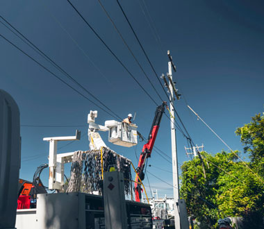 contractor up in bucket truck next to power pole