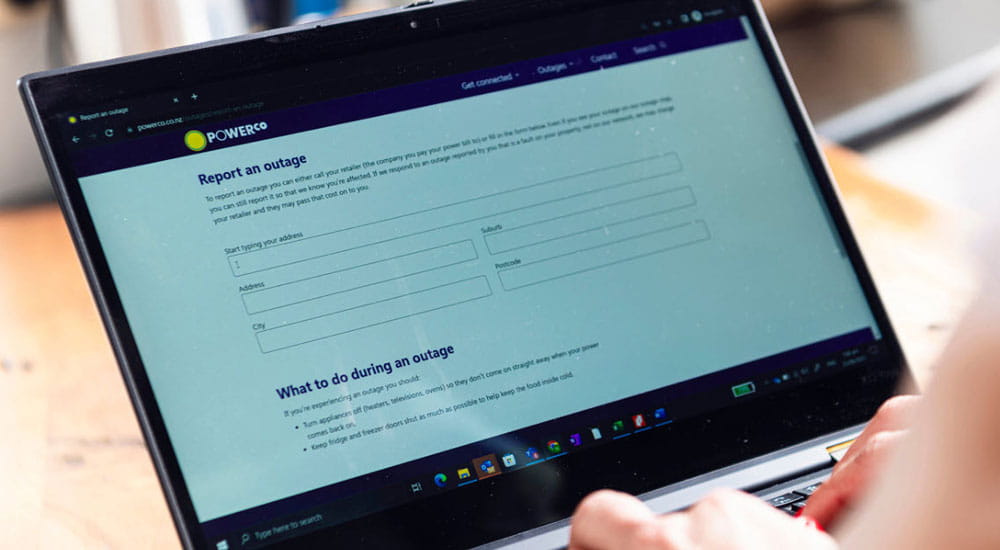 person working on laptop looking at report an outage page