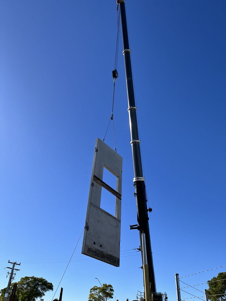 A concrete wall panel being transported through the air via a crane