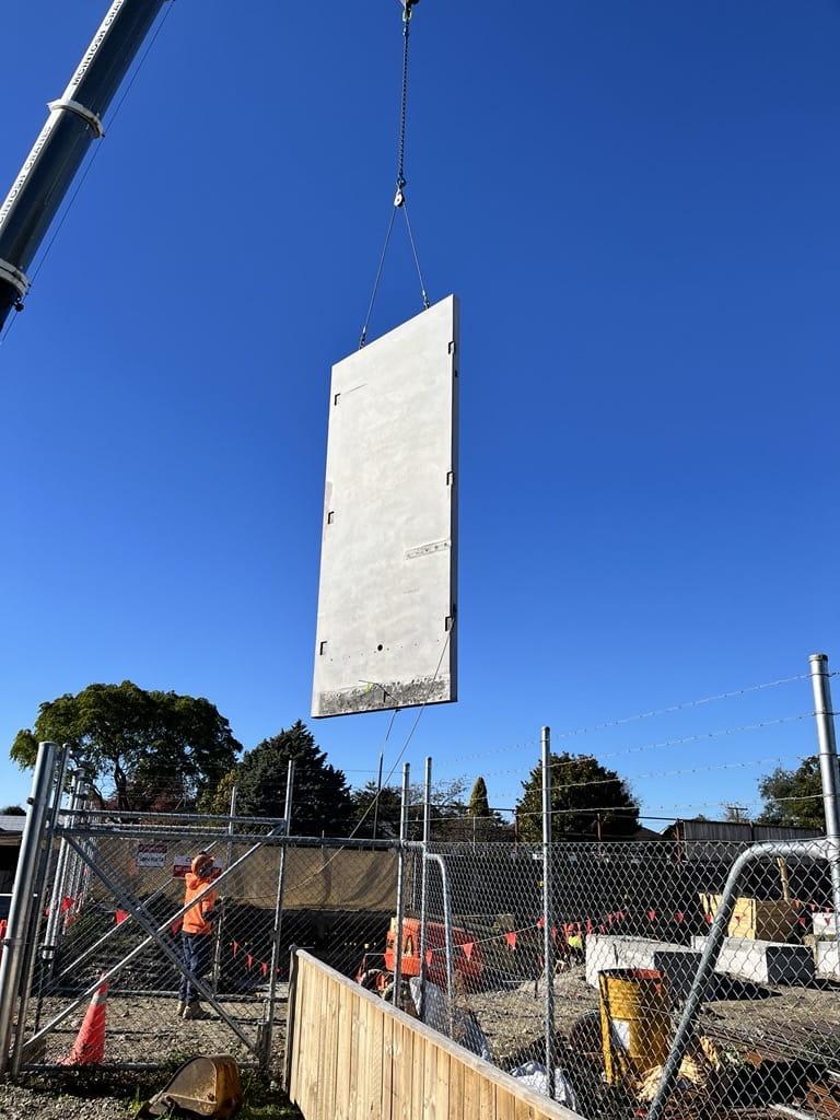 A concrete panel being transported through the air via a crane
