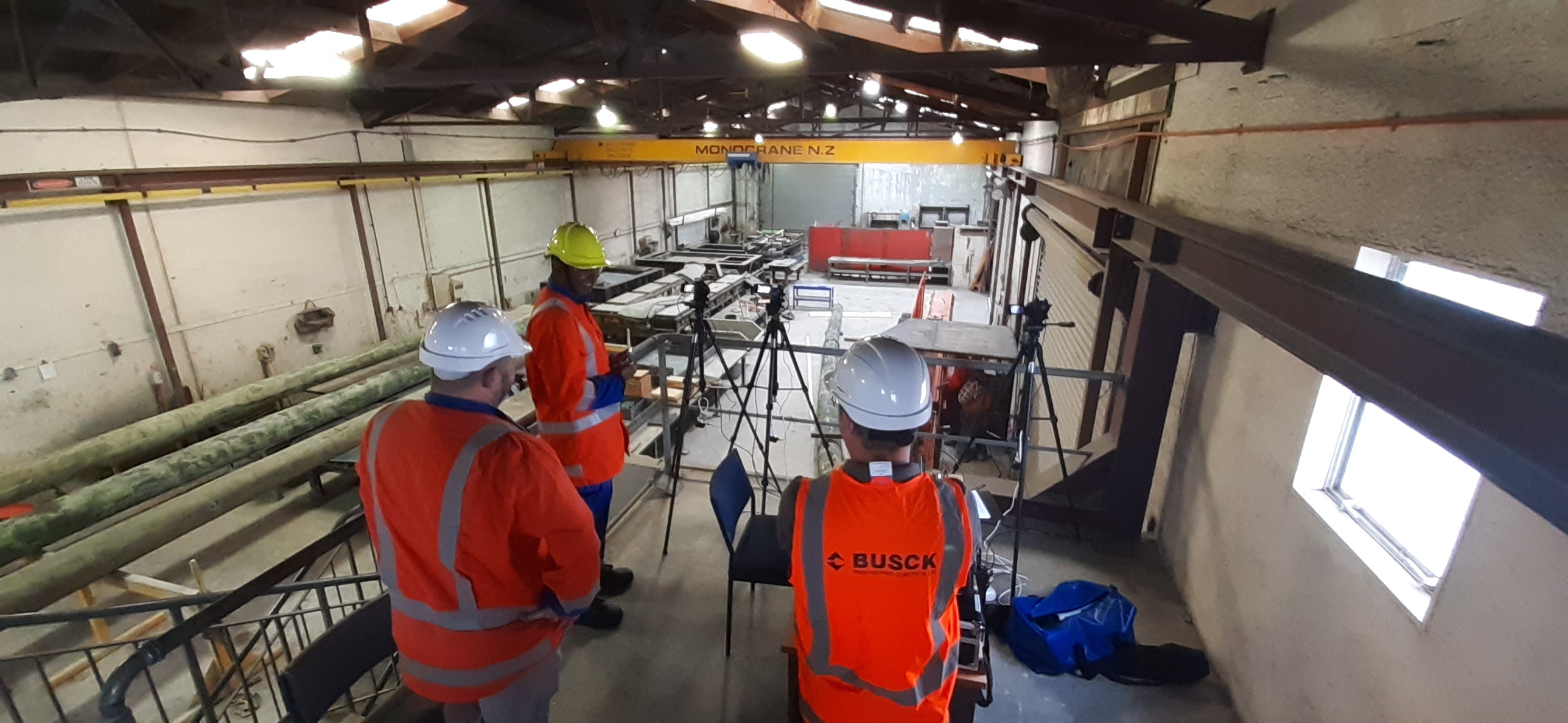 Powerco team members in high-vis observing an indoor controlled pole break test