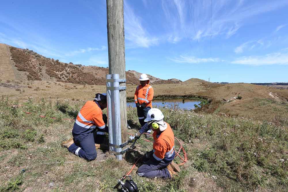 Field crew reinforcing a wooden pole