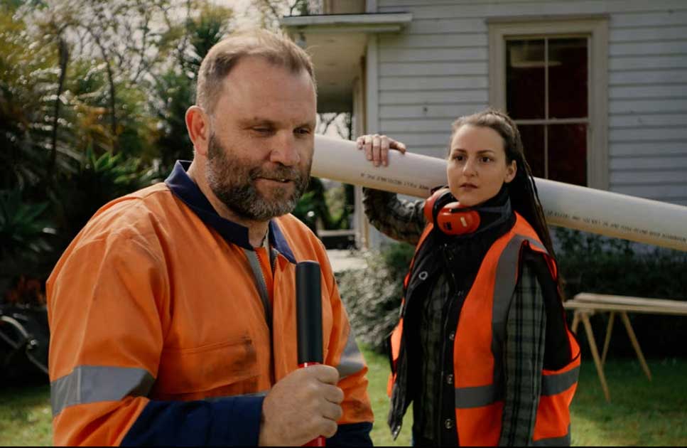 man holding shovel and woman carrying ducting in back yard